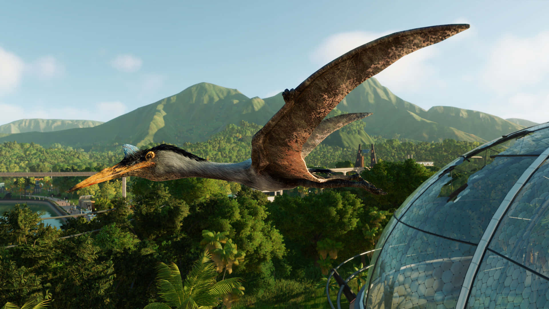 Jurassic World 桌布 壁紙 — 一隻大型翼龍優雅地翱翔於茂密的綠色叢林之上，背景有山脈，附近還有一座玻璃圓頂結構。
