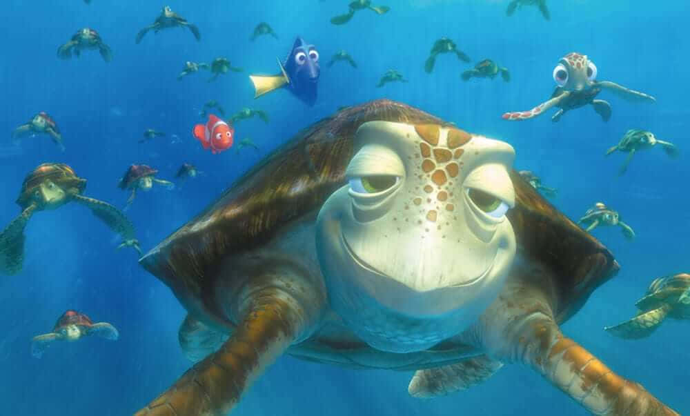 Cartoon Turtle 桌布 壁紙 — 一隻大海龜在清澈的藍色海水中平靜地游動，周圍環繞著較小的海龜和色彩繽紛的魚類。
