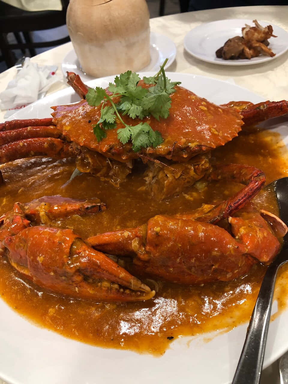螃蟹 桌布 壁紙 — 一隻完整的蒸蟹，配上濃郁的橙醬，飾以新鮮香菜，放在白色盤子上，在餐廳環境中。