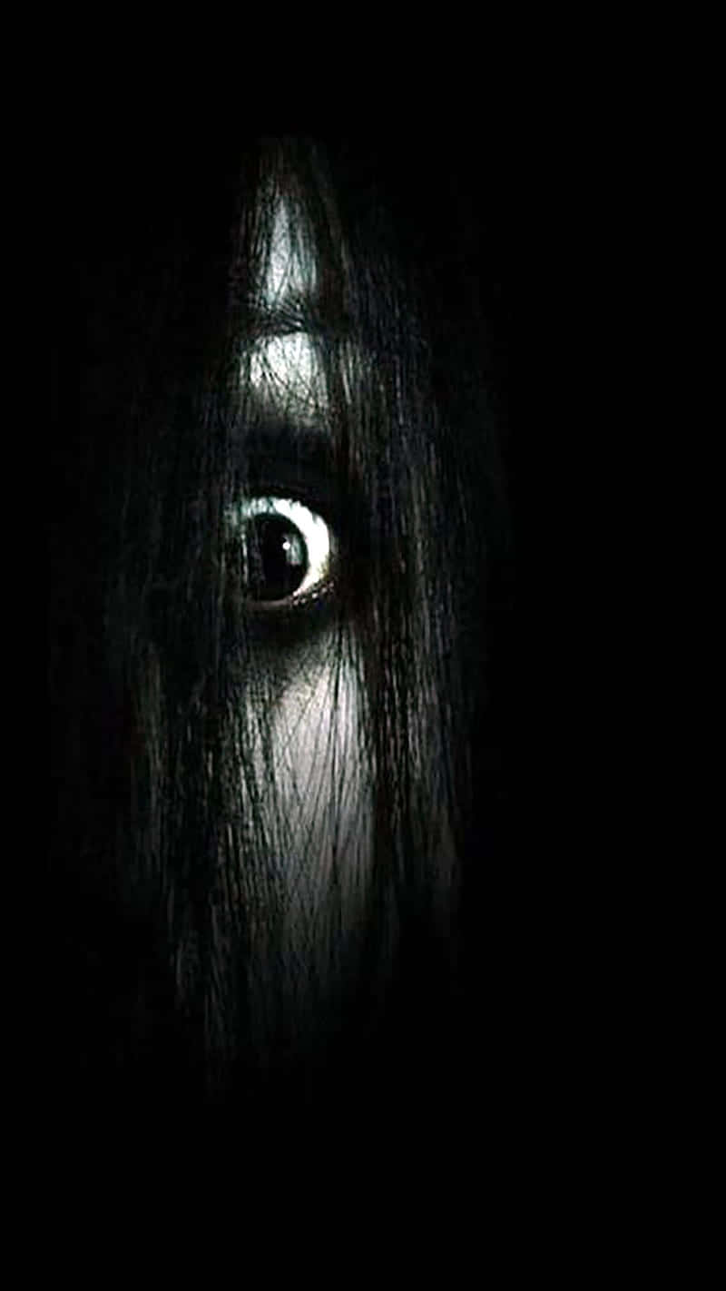 Creepy Halloween 桌布 壁紙 — 一隻寬大的眼睛在完全黑暗中透過深色頭髮窺視，營造出令人毛骨悚然的恐怖效果。