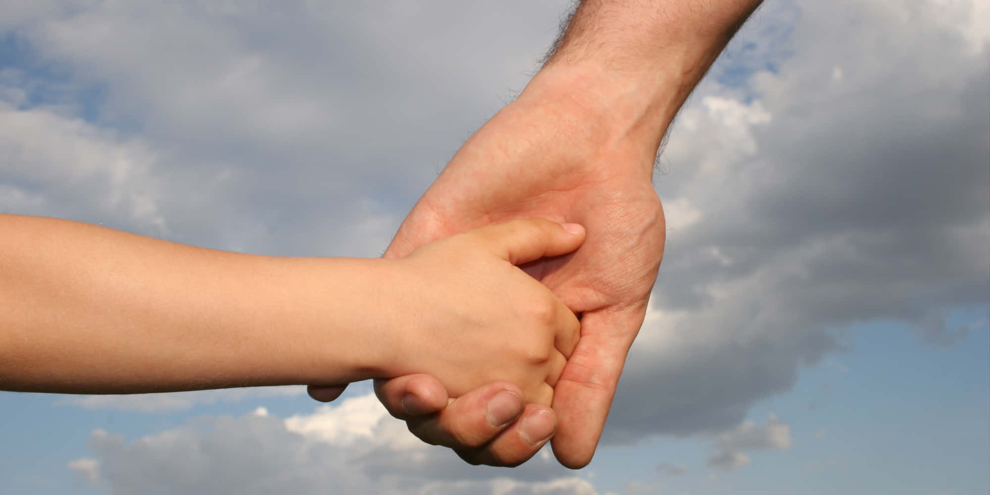 Father And Son 桌布 壁紙 — 一隻小孩的小手抓住一隻大人的大手，背景是藍天和白雲。