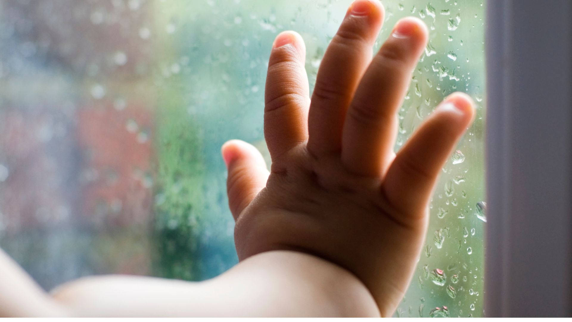 hand 桌布 壁紙 — 一隻小孩的小手按在沾滿雨點的窗戶上，窗外模糊的色彩隱約可見。