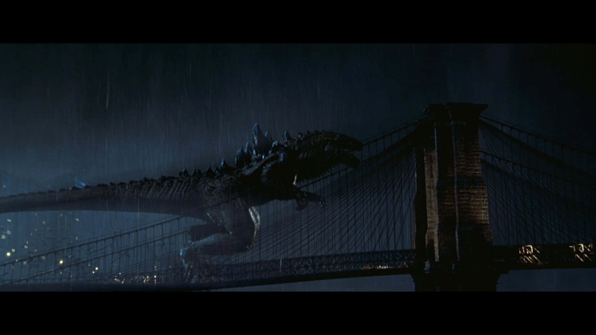 godzilla 1998 桌布 壁紙 — 一隻巨大的哥吉拉在黑暗暴風雨的夜空下，大步走過濕滑的吊橋。
