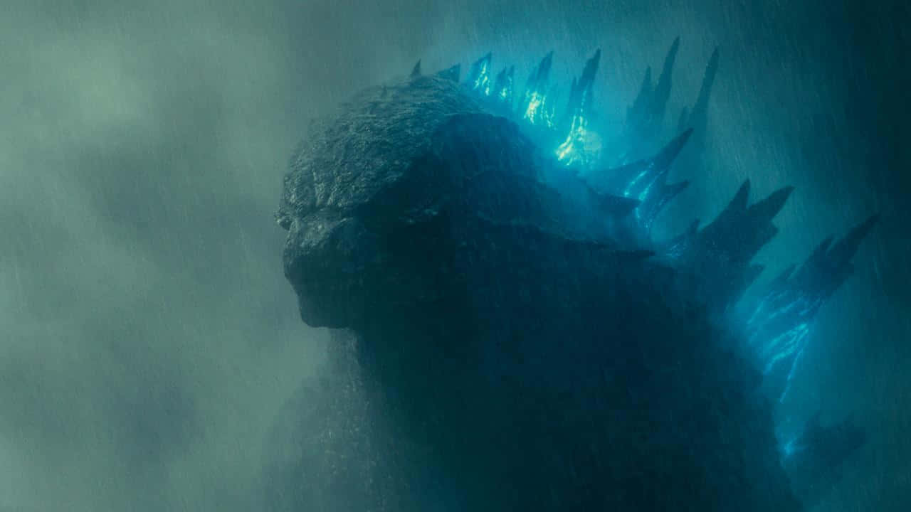 Burning Godzilla 桌布 壁紙 — 一隻巨大的哥吉拉從渾濁的水中浮現，發光的藍色背鰭劃破迷霧深處。
