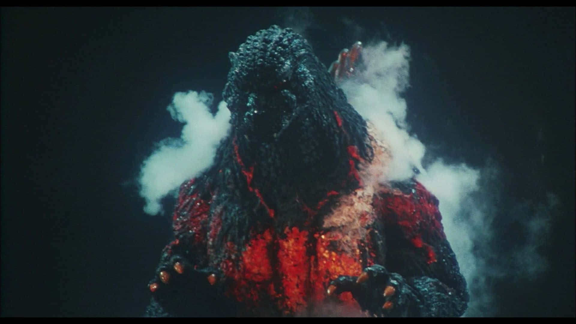 Godzilla 1954 桌布 壁紙 — 一隻巨大的哥吉拉從煙霧中出現，發光的紅色岩漿流過其燒焦的身體，背景漆黑。