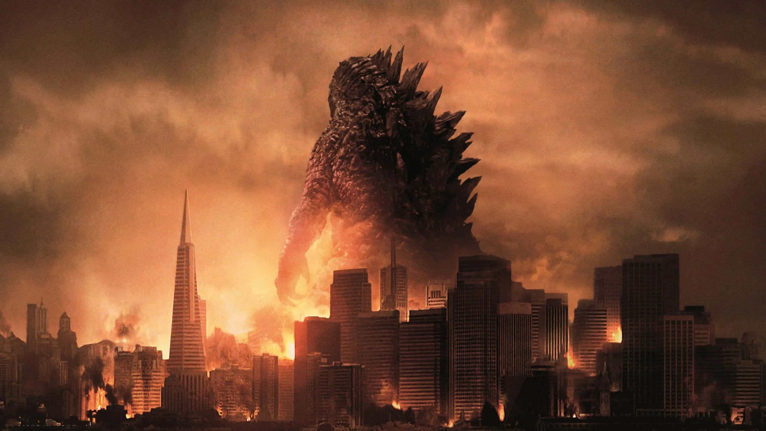 monsters 桌布 壁紙 — 一隻巨大的哥吉拉聳立在燃燒的城市景觀之上，火焰和煙霧從倒塌的摩天大樓中升起，在末日般的橙色天空下。
