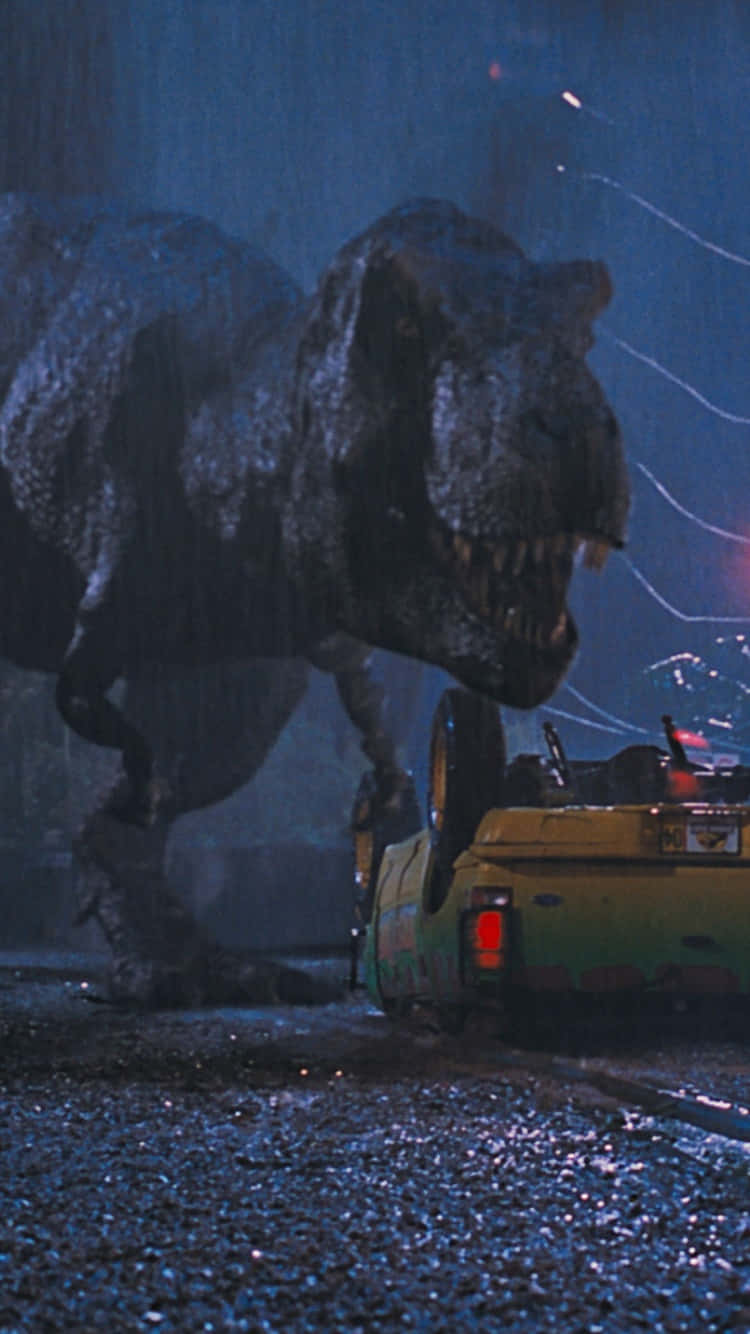 Jurassic Park Zoom 桌布 壁紙 — 一隻巨大的暴龍在雨夜場景中籠罩著一輛被壓碎的黃色汽車。