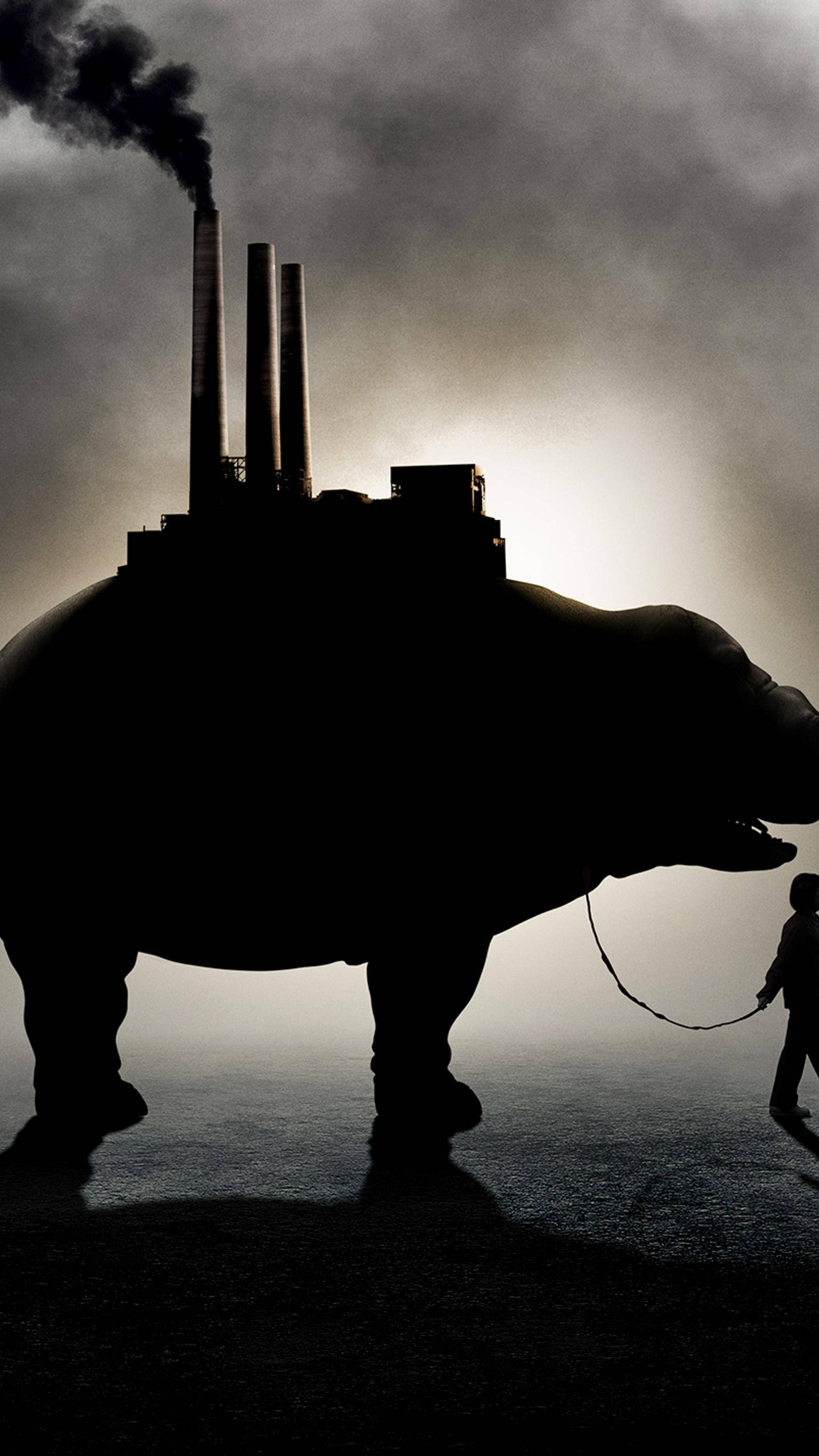 okja 桌布 壁紙 — 一隻巨大的河馬剪影背著一座工業工廠，一個小人影在旁邊走著，牽著一條皮帶。