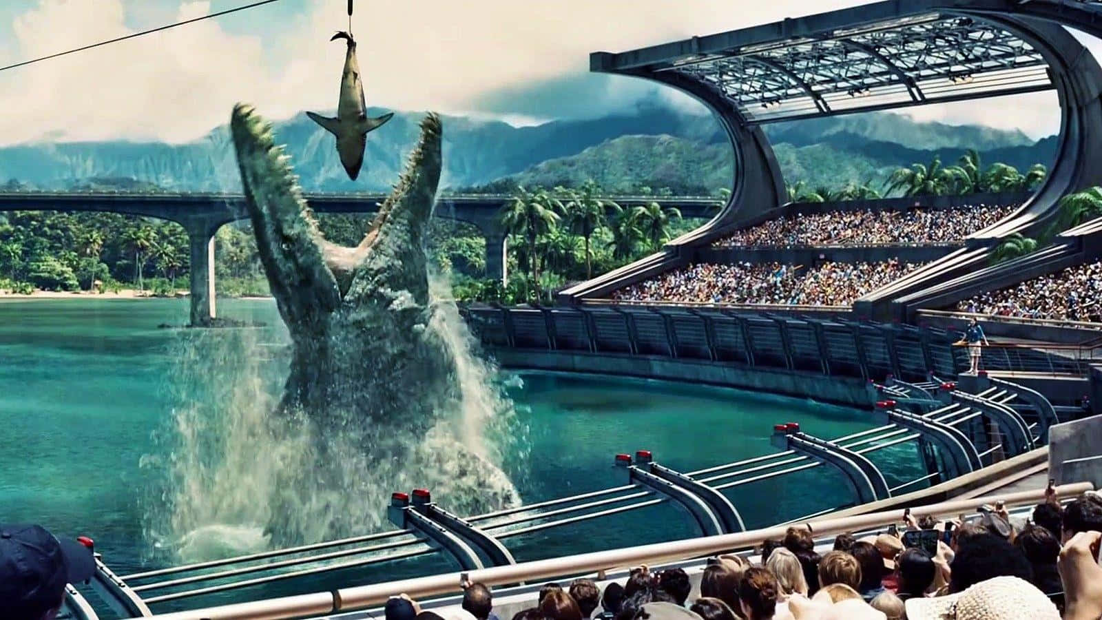Jurassic World 桌布 壁紙 — 一隻巨大的滄龍在未來主題樂園中，在咆哮的人群面前衝破一個藍綠色的水缸。