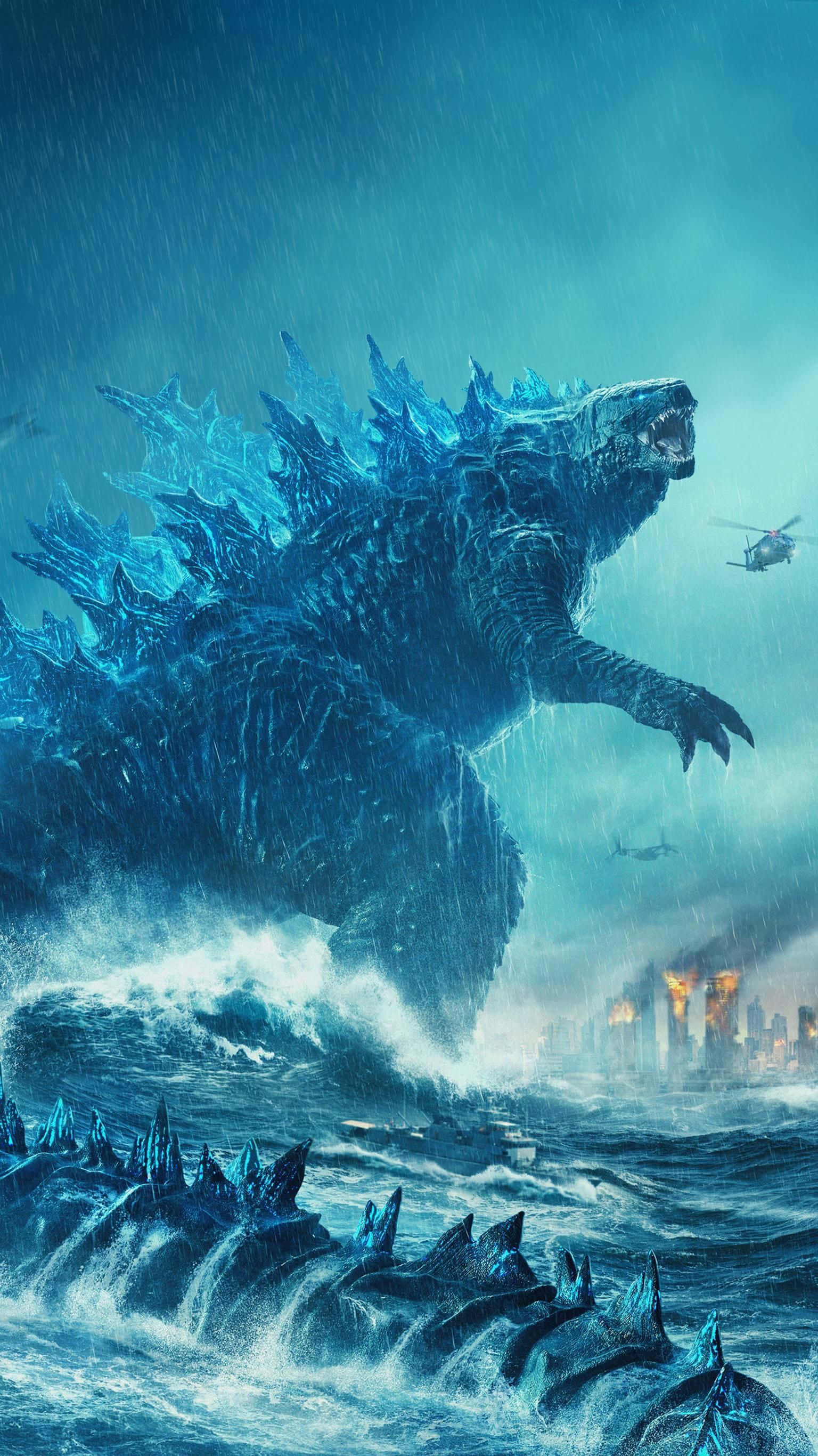 Classic Godzilla 桌布 壁紙 — 一隻巨大的藍色哥吉拉從暴風雨的海浪中出現，直升機在頭頂飛過，遠處是一座燃燒的城市。