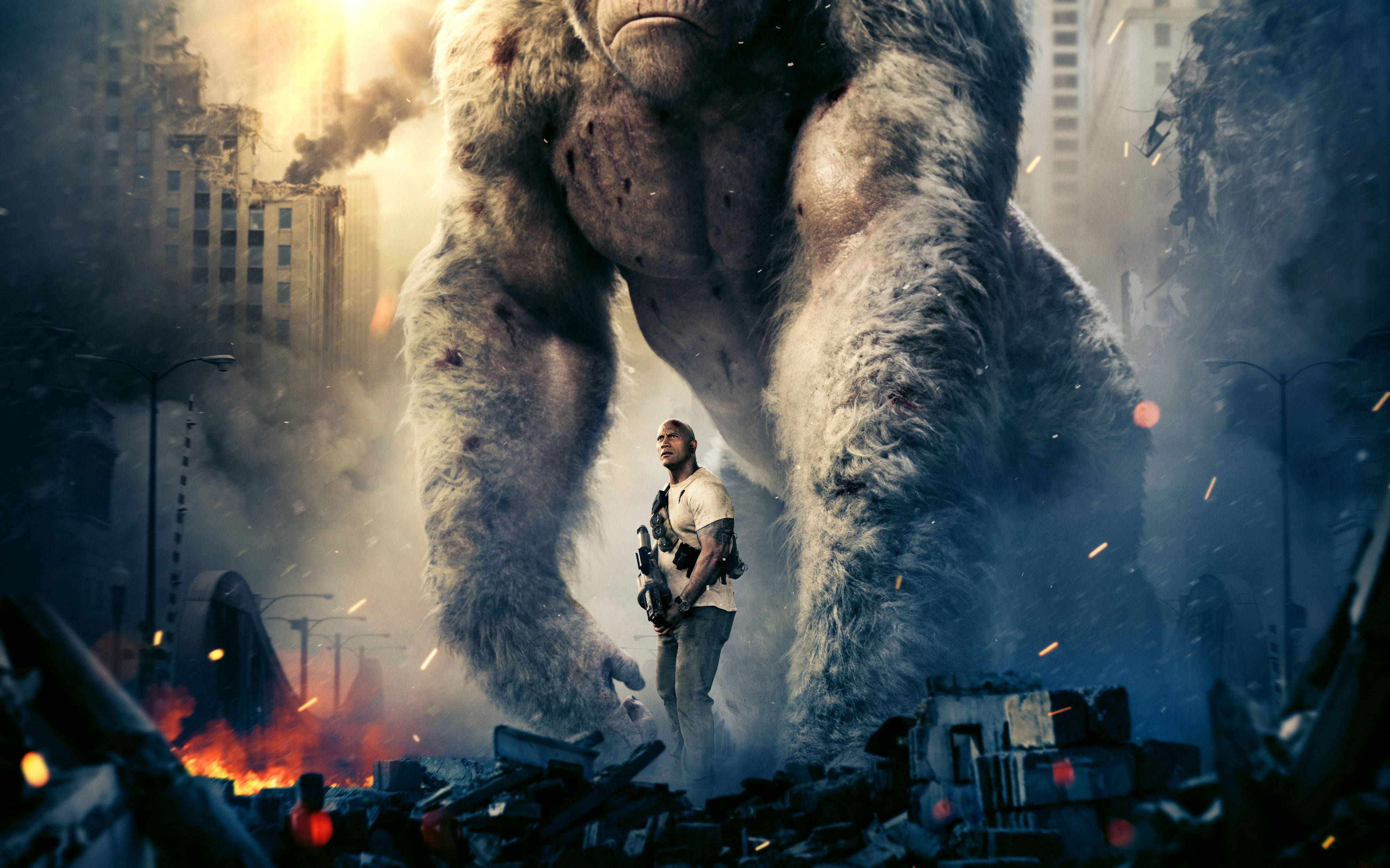 The Rock 桌布 壁紙 — 一隻巨猿在日落時分，聳立於一個手持武器的人類之上，四周是燃燒中的廢墟城市景觀。