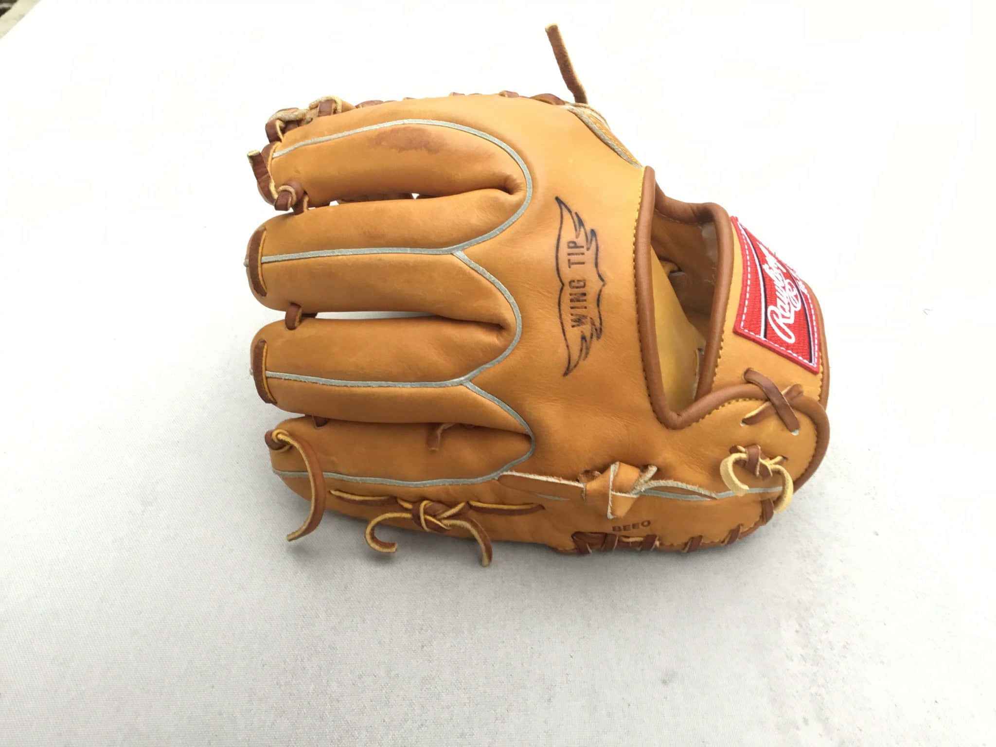 Baseball Gloves 桌布 壁紙 — 一隻帶有 'Wing Tip' 品牌標誌的棕褐色皮革棒球手套放在純白色表面上。