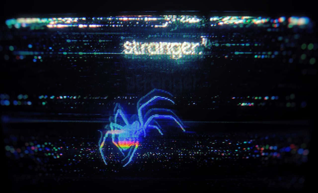 glitch art 桌布 壁紙 — 一隻帶有彩虹腹部的故障數位蜘蛛在顯示「Stronger」字樣的黑暗螢幕上發光。