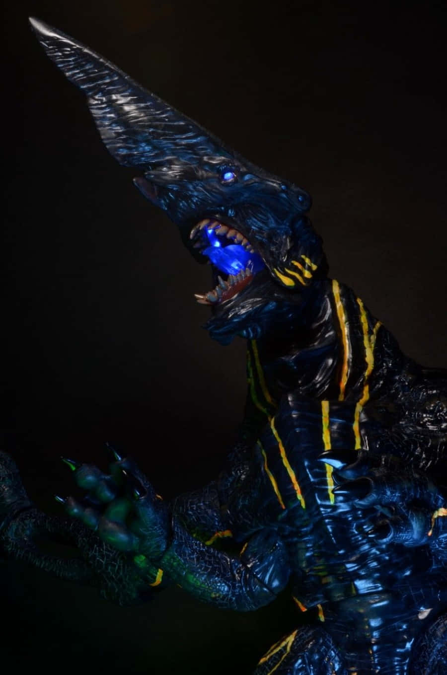 Kaiju 桌布 壁紙 — 一隻帶有發光眼睛和尖銳牙齒的威脅性藍黃色怪獸在黑暗背景下咆哮。