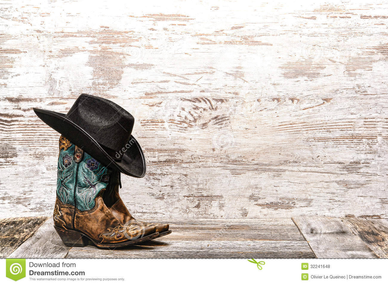 American Cowboy 桌布 壁紙 — 一隻帶有綠松石刺繡的華麗牛仔靴和黑色帽子放在風化的木板上，背景是質樸的白色牆壁。