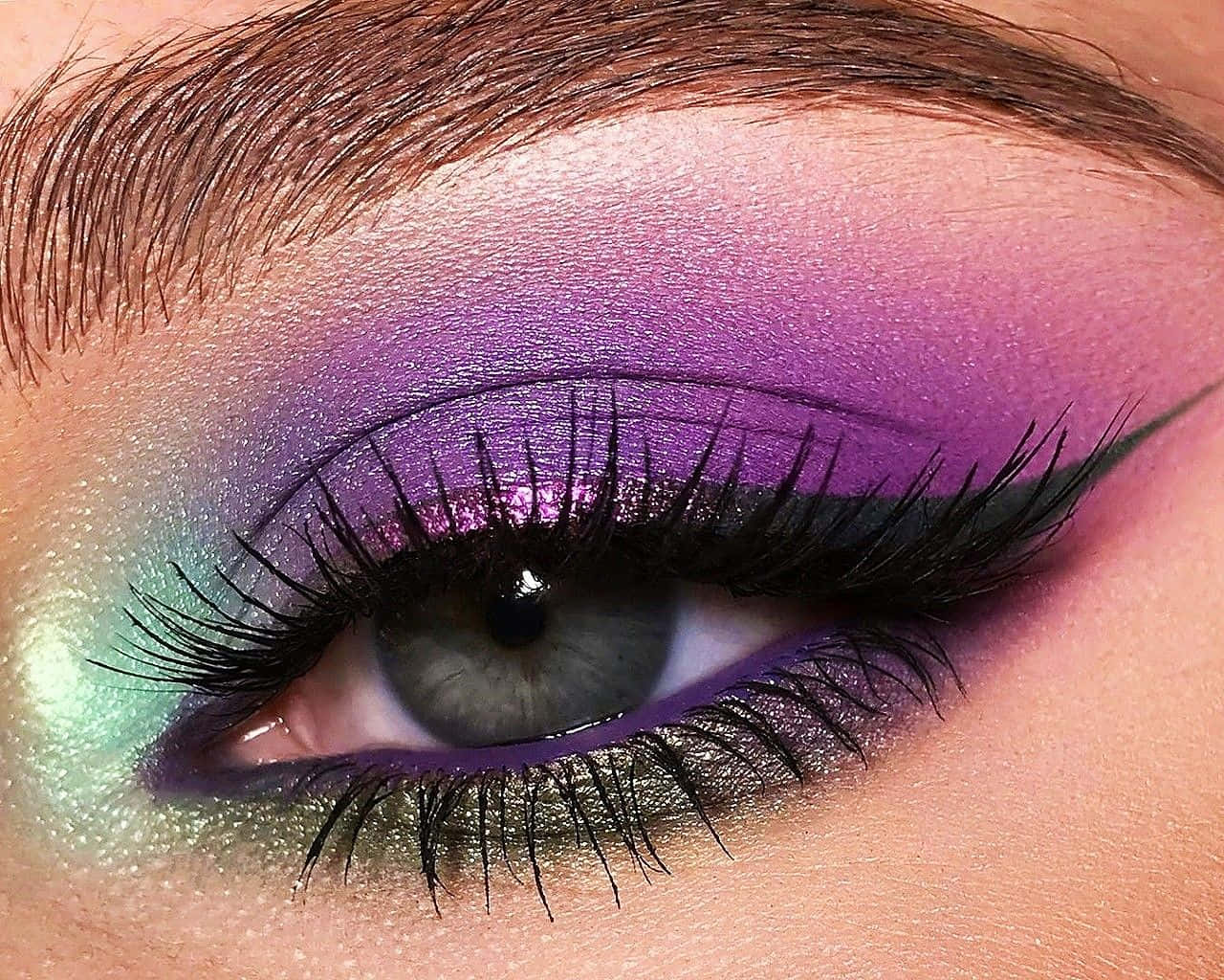 Purple Eye Shadow 桌布 壁紙 — 一隻引人注目的眼睛特寫，帶有充滿活力的紫色和藍綠色閃粉眼影以及戲劇性的黑色睫毛。