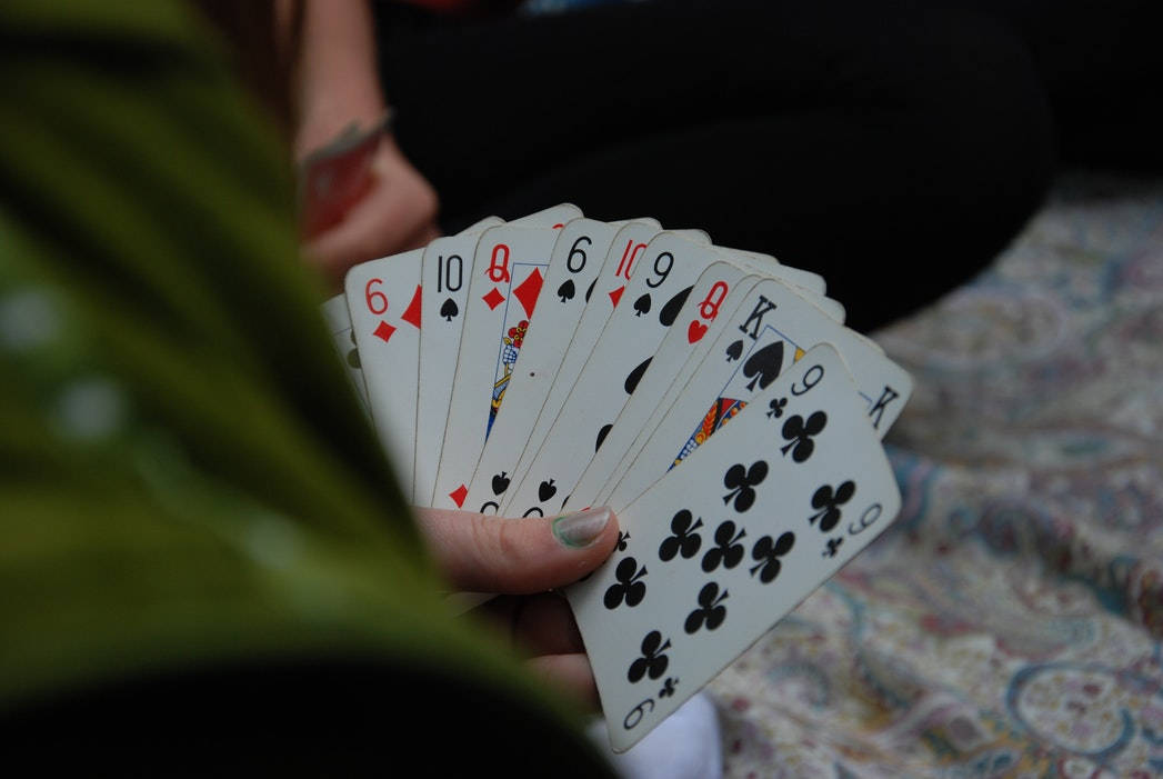 Casino 桌布 壁紙 — 一隻張開的手拿著撲克牌，一片綠葉部分遮擋了視線。