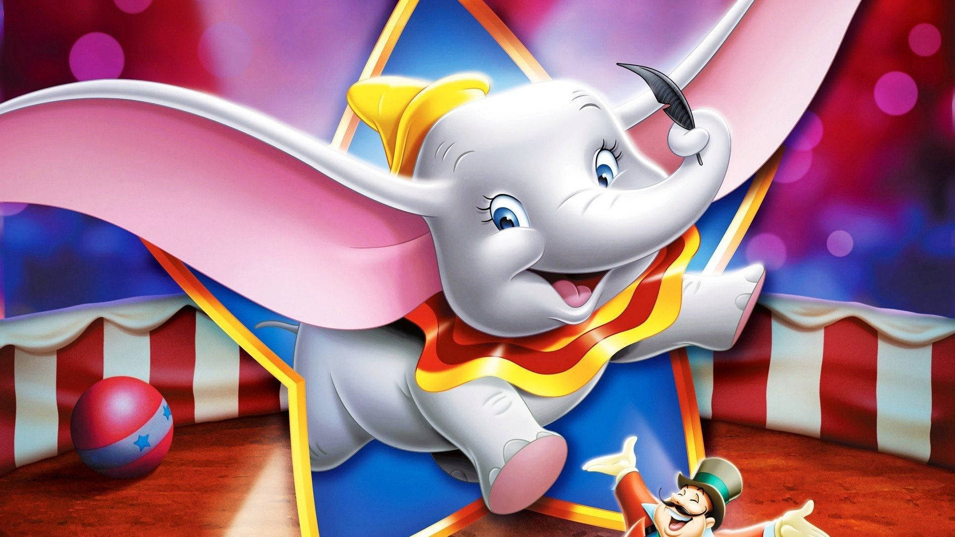 Dumbo 桌布 壁紙 — 一隻快樂的動畫大象，長著粉紅色翅膀，戴著黃色帽子，愉快地飛過馬戲團帳篷，下面有一個小丑。