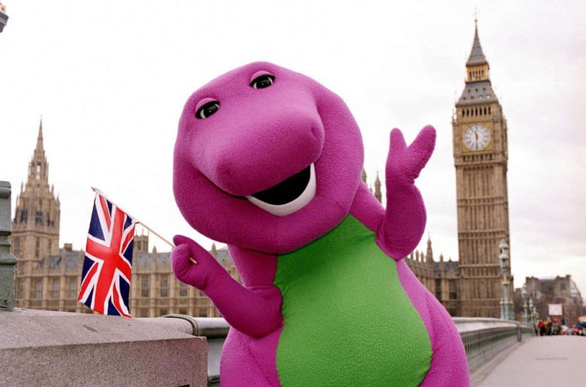 barney 桌布 壁紙 — 一隻快樂的粉紅色巴尼吉祥物在倫敦橋上揮舞英國國旗，背景是大笨鐘。