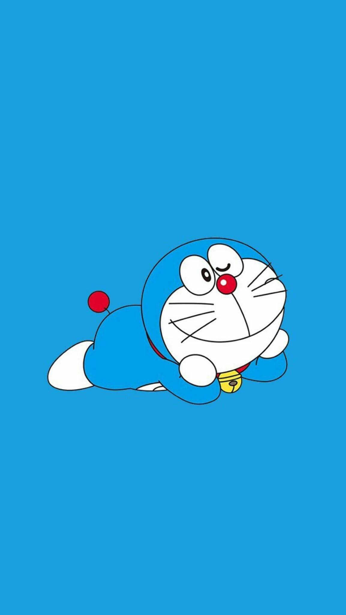 Doraemon 桌布 壁紙 — 一隻快樂的藍色機器貓，有紅色鼻子和鈴鐺，躺在純藍色背景上。
