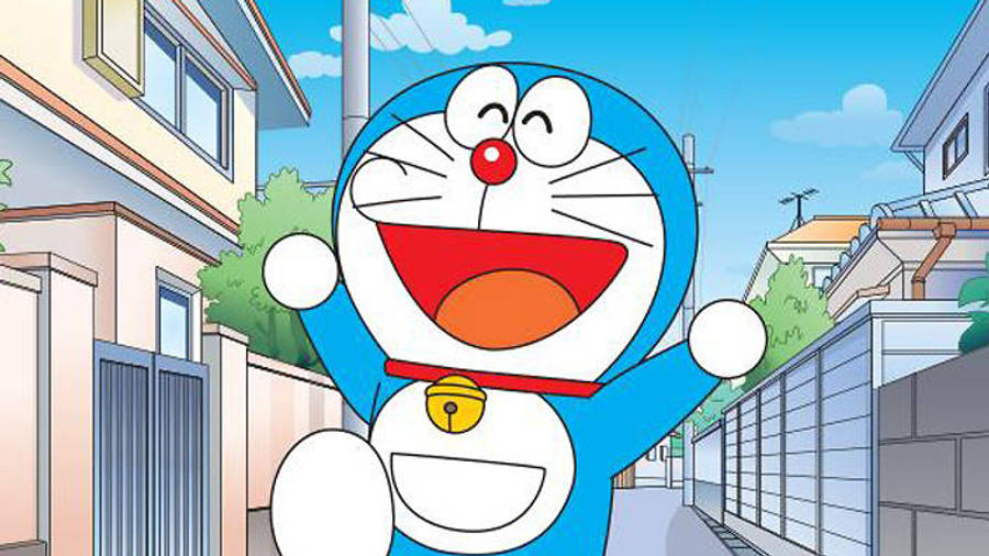doraemon 4K 桌布 壁紙 — 一隻快樂的藍色機器貓，紅鼻子，咧嘴大笑，愉快地站在陽光的郊區小巷裡。