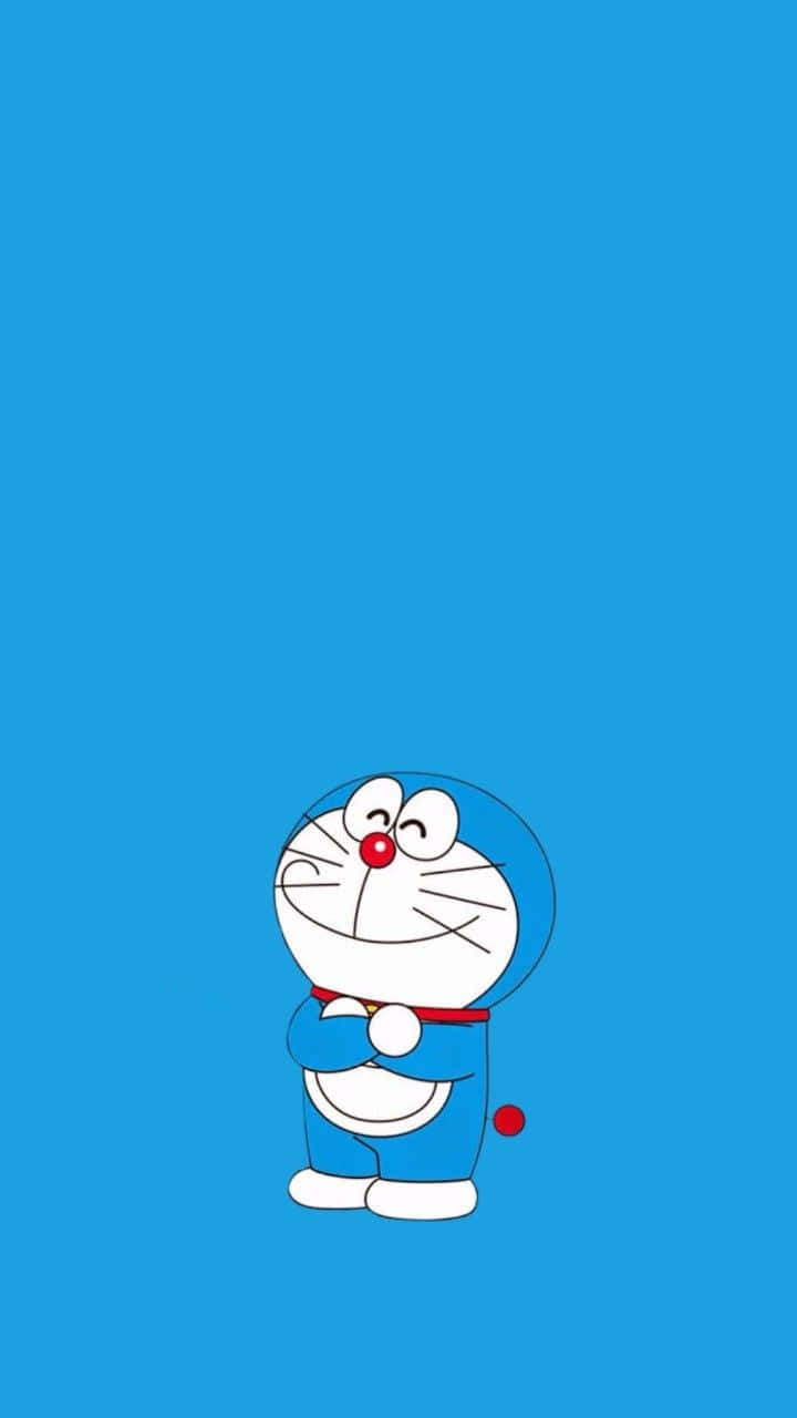 Doraemon 桌布 壁紙 — 一隻快樂的藍色機械貓，紅鼻子白肚皮，獨自站在純藍色背景前。