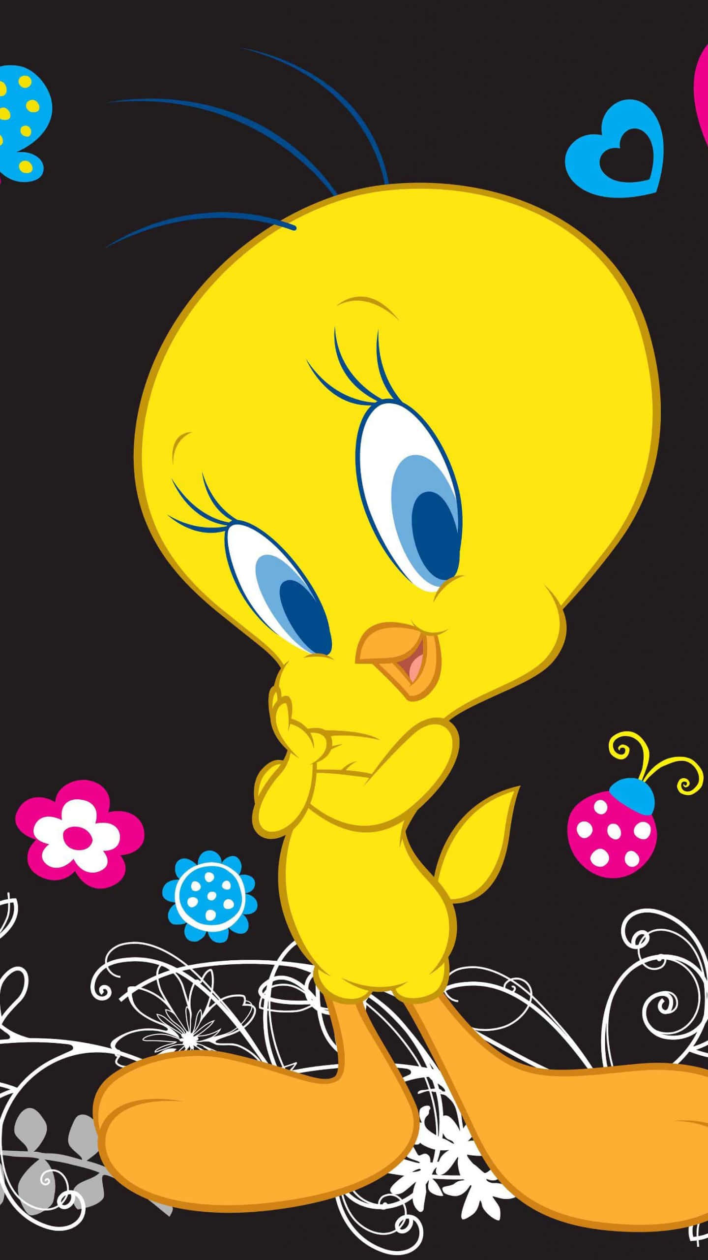 Tweety Bird 桌布 壁紙 — 一隻快樂的黃色卡通鳥，有大大的藍色眼睛和可愛的紅暈，站在深色背景前，周圍有色彩繽紛的花朵和心形裝飾。