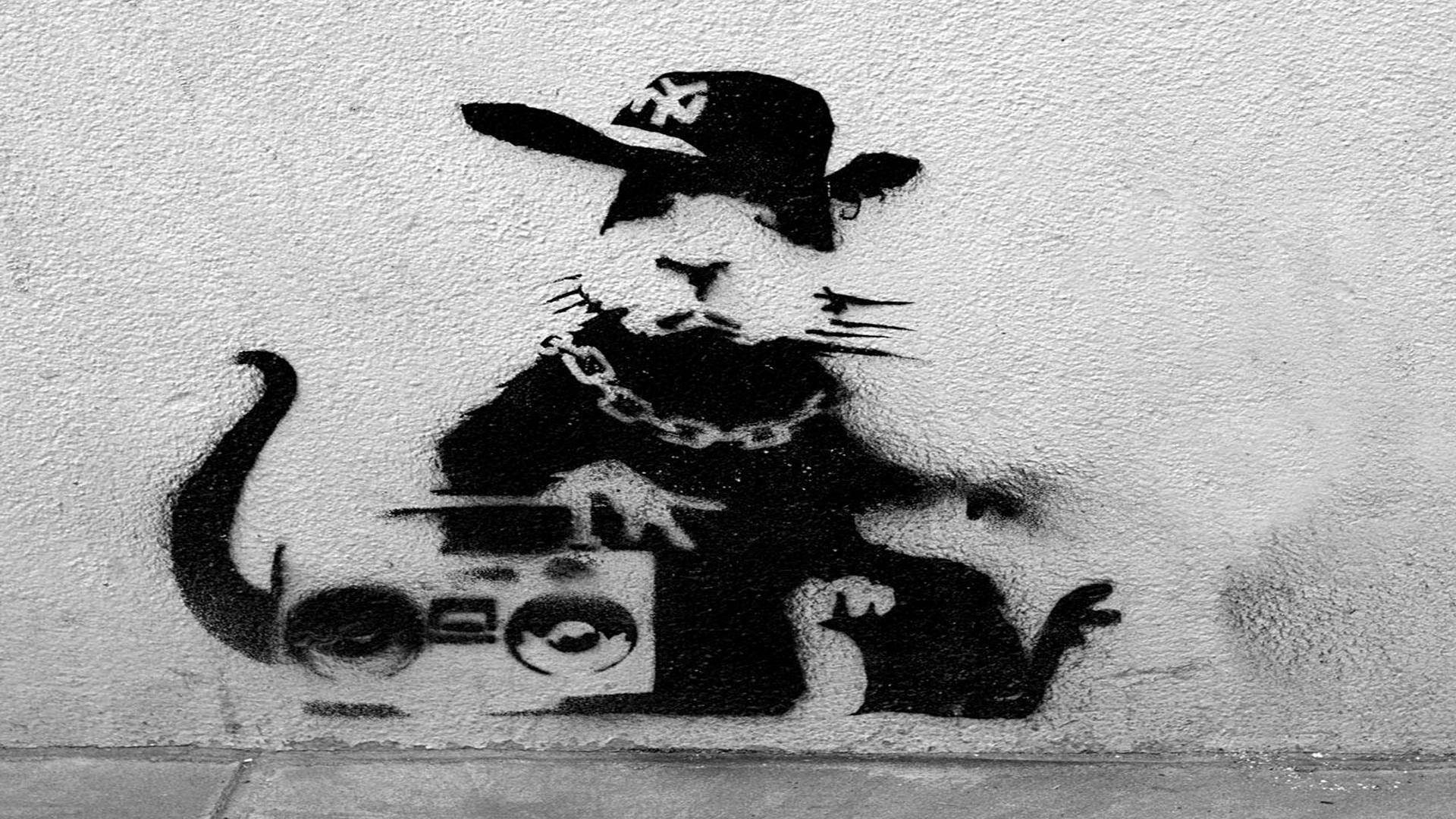 Banksy 桌布 壁紙 — 一隻戴帽子和鏈條的老鼠在紋理牆上拿著手提音箱的黑白模板塗鴉。