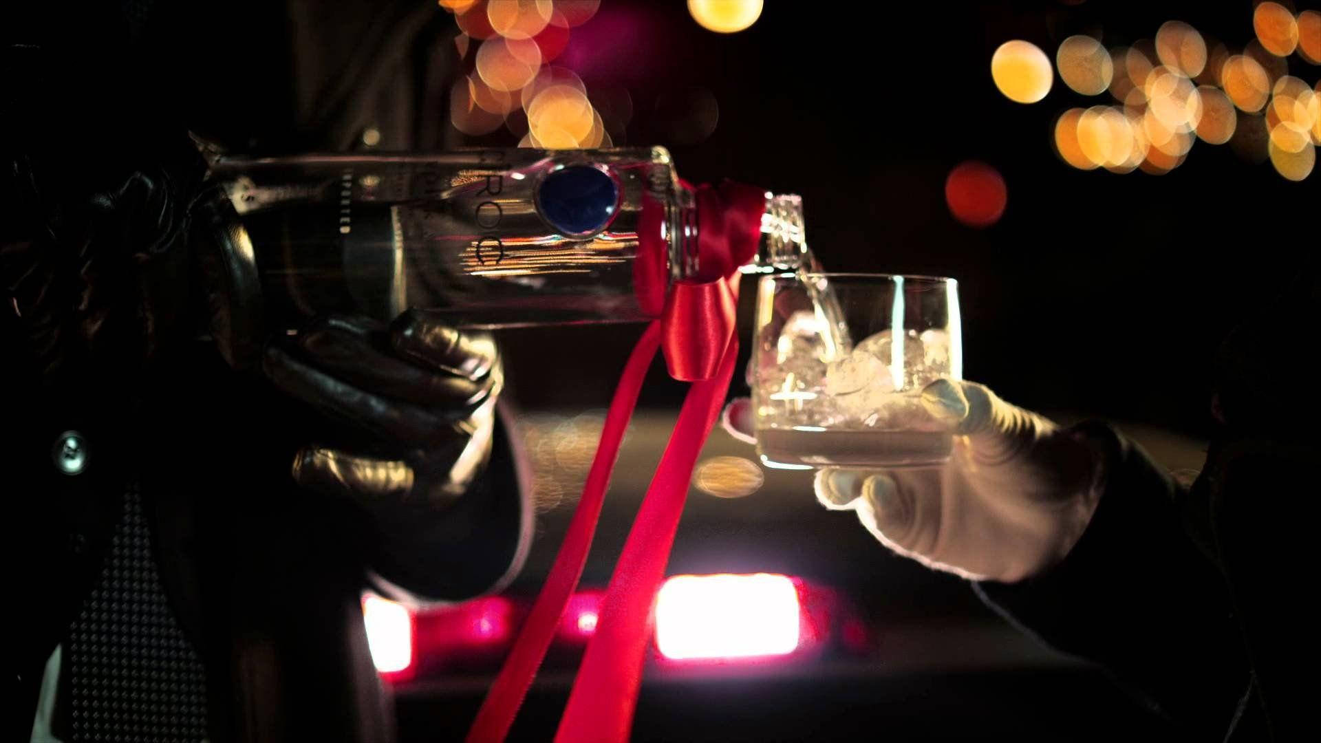 Drink 桌布 壁紙 — 一隻戴著手套的手將一瓶帶有紅色絲帶的伏特加倒入裝滿冰塊的玻璃杯中，背景是黑暗的散景燈光。