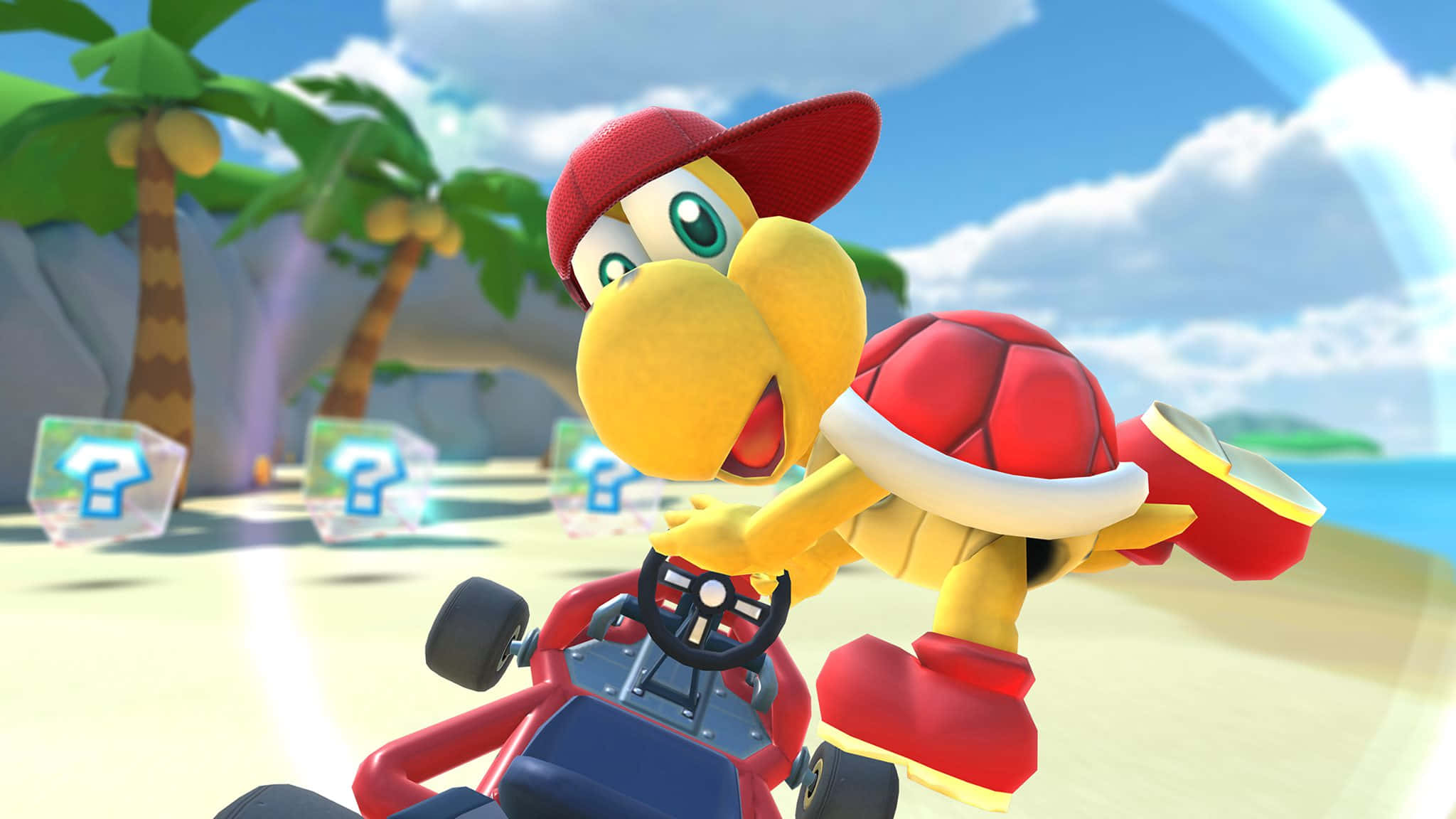 Koopa Troopa 桌布 壁紙 — 一隻戴著紅帽子的快樂黃色烏龜在陽光明媚的熱帶海灘上，有棕櫚樹和問號方塊，進行卡丁車比賽。