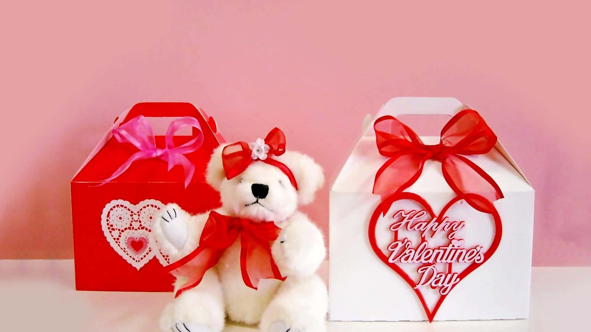 Teddy Bear 桌布 壁紙 — 一隻戴著紅色蝴蝶結的白色泰迪熊坐在兩個裝飾著愛心和緞帶的情人節禮物盒之間，背景是柔和的粉紅色。