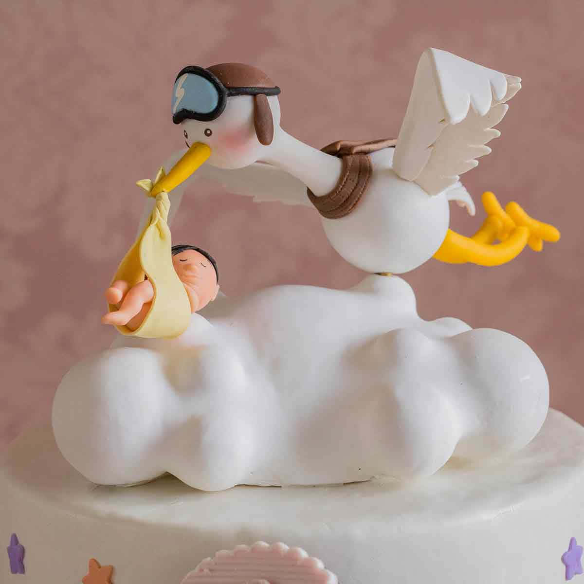 Cake Fondant 桌布 壁紙 — 一隻戴著飛行員護目鏡的俏皮翻糖鸛鳥，棲息在蛋糕頂部的蓬鬆白雲上，運送一個黃色包裹中的嬰兒。