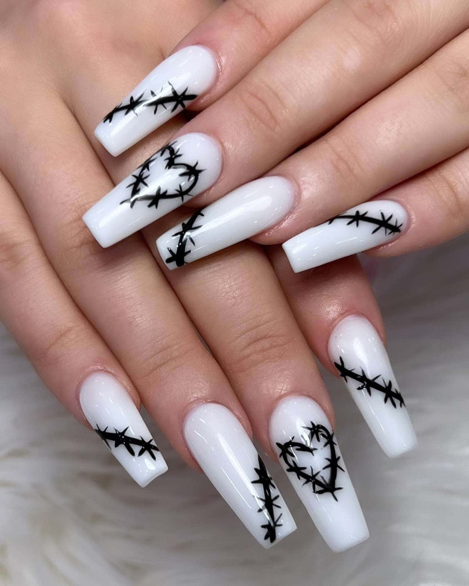 Halloween Nail Art 桌布 壁紙 — 一隻手，帶有長長的白色細高跟指甲，飾有黑色鐵絲網設計，背景是柔軟的白色毛絨。