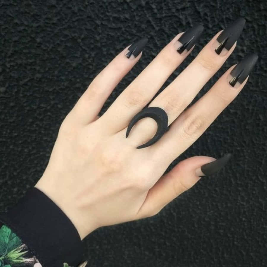 Nail Polish 桌布 壁紙 — 一隻手，帶有長黑色啞光指甲和一個新月戒指，背景為深色紋理。