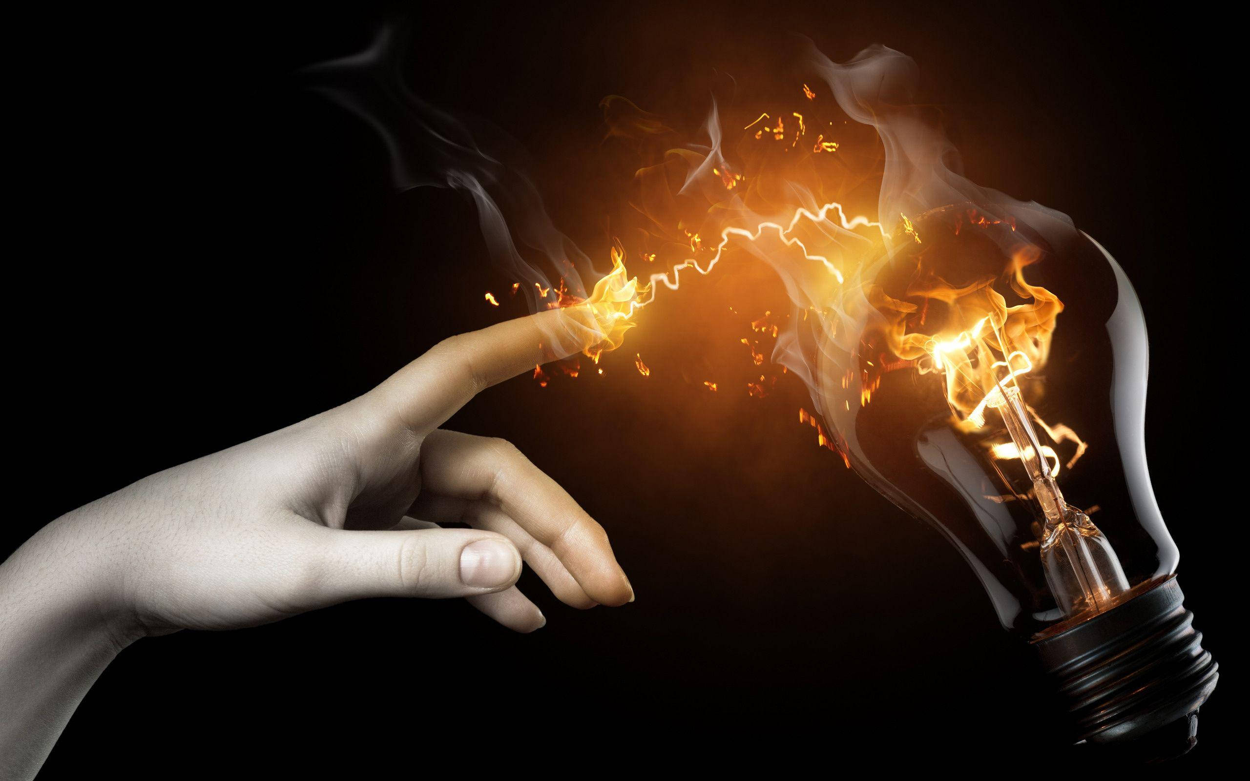 finger pointing 桌布 壁紙 — 一隻手伸向一個燃燒的燈泡，指尖和燈泡之間有電火花飛舞，背景為黑色。