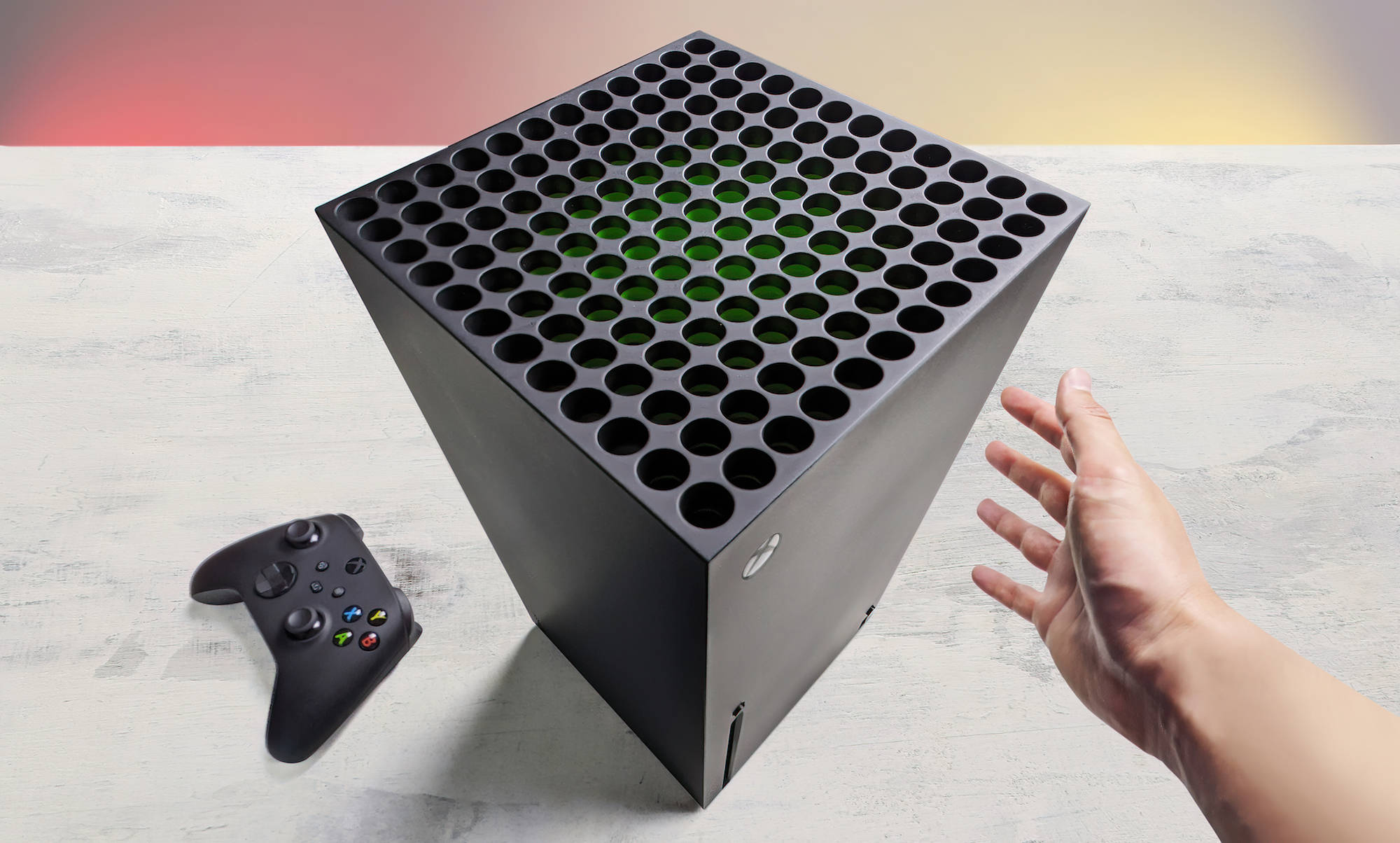 X 桌布 壁紙 — 一隻手伸向黑色Xbox Series X主機，內部發出綠色光芒，旁邊是其控制器，放在淺灰色表面上。