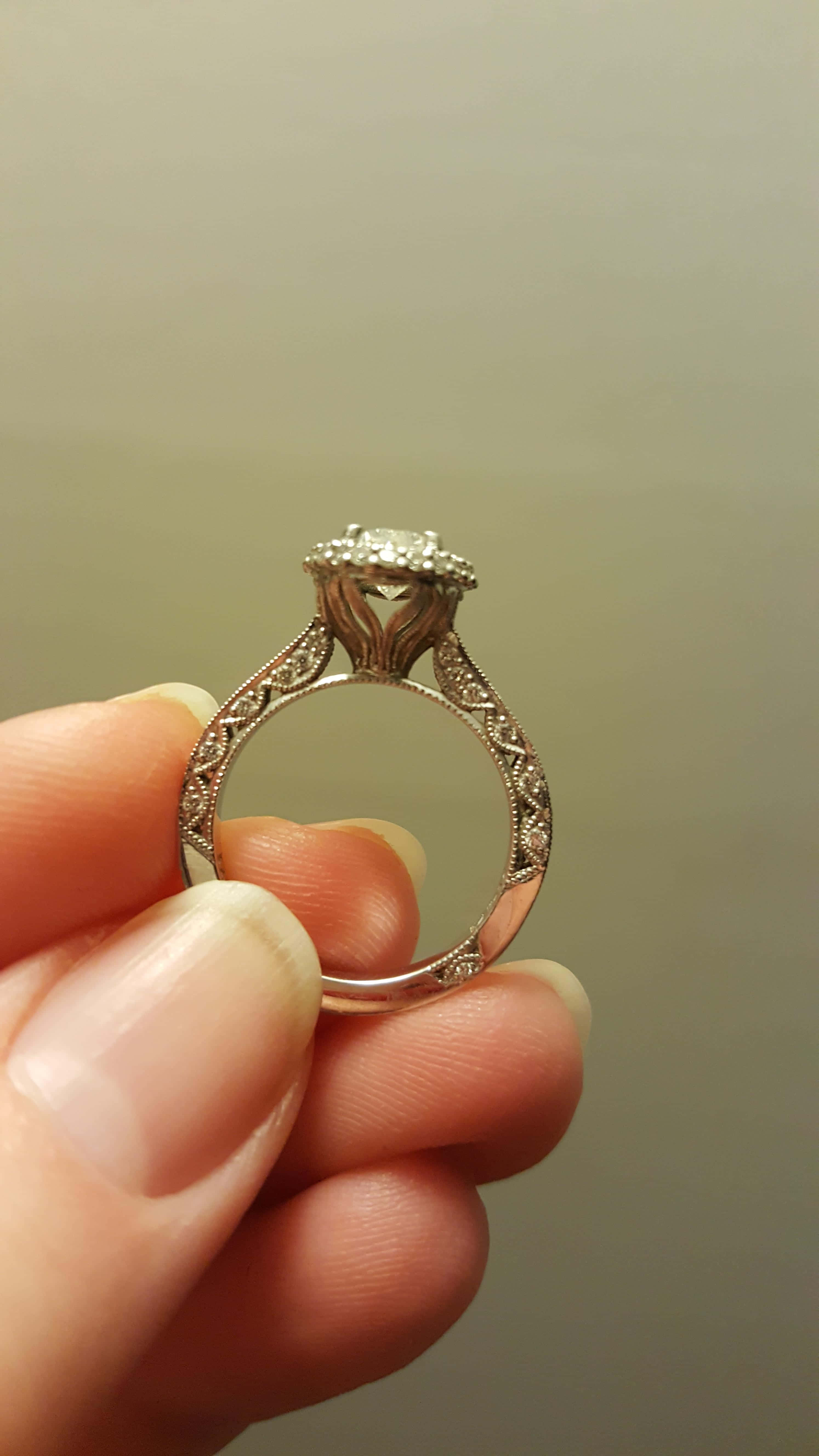 rings 桌布 壁紙 — 一隻手優雅地拿著一枚復古風格的鑽石戒指，帶有精緻的鏤空花絲和光環鑲嵌，背景柔和模糊。