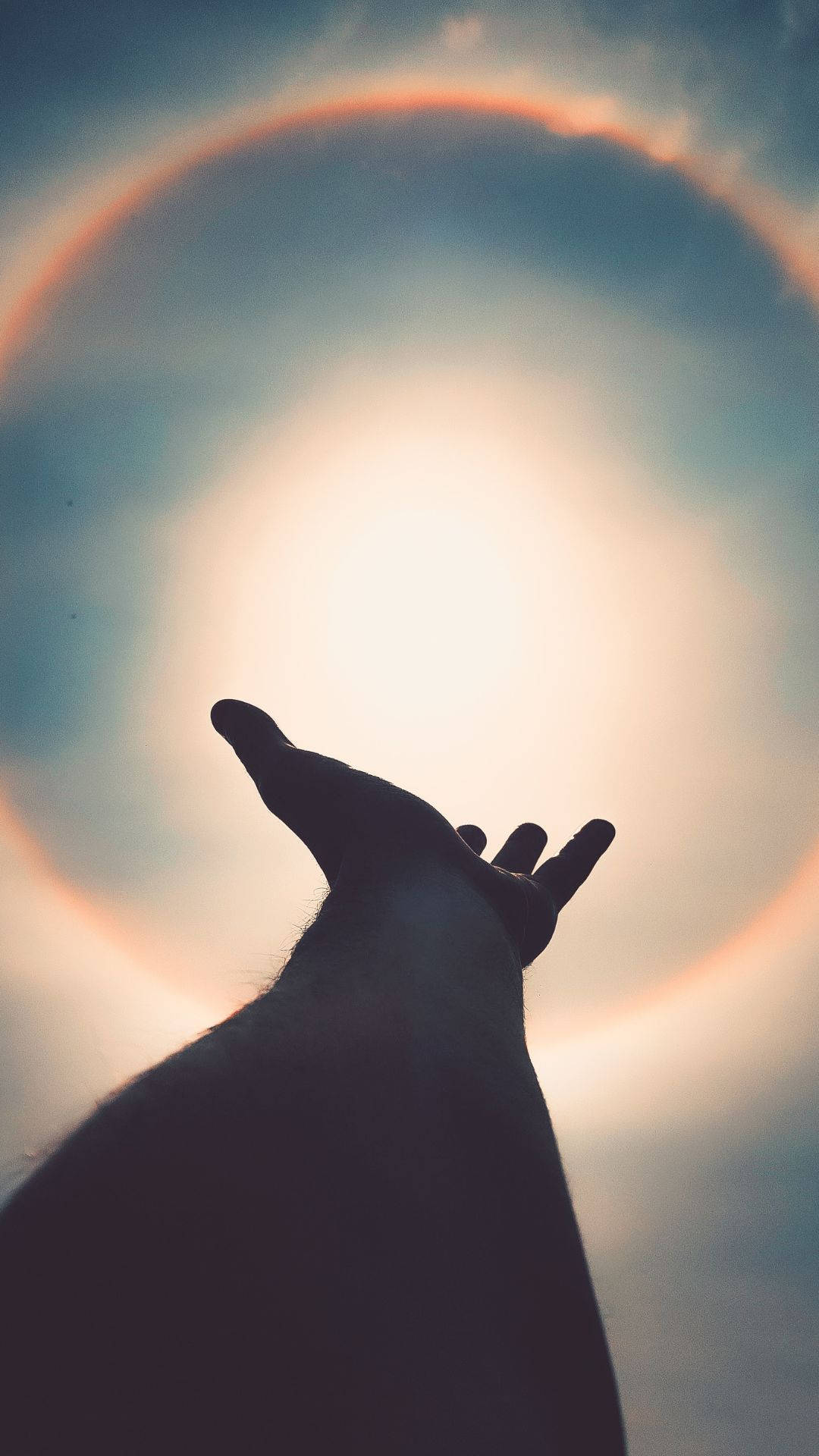 抽象 桌布 壁紙 — 一隻手向上伸向一個發光的太陽，周圍環繞著鮮明的大氣光暈，背景是柔和的藍天。