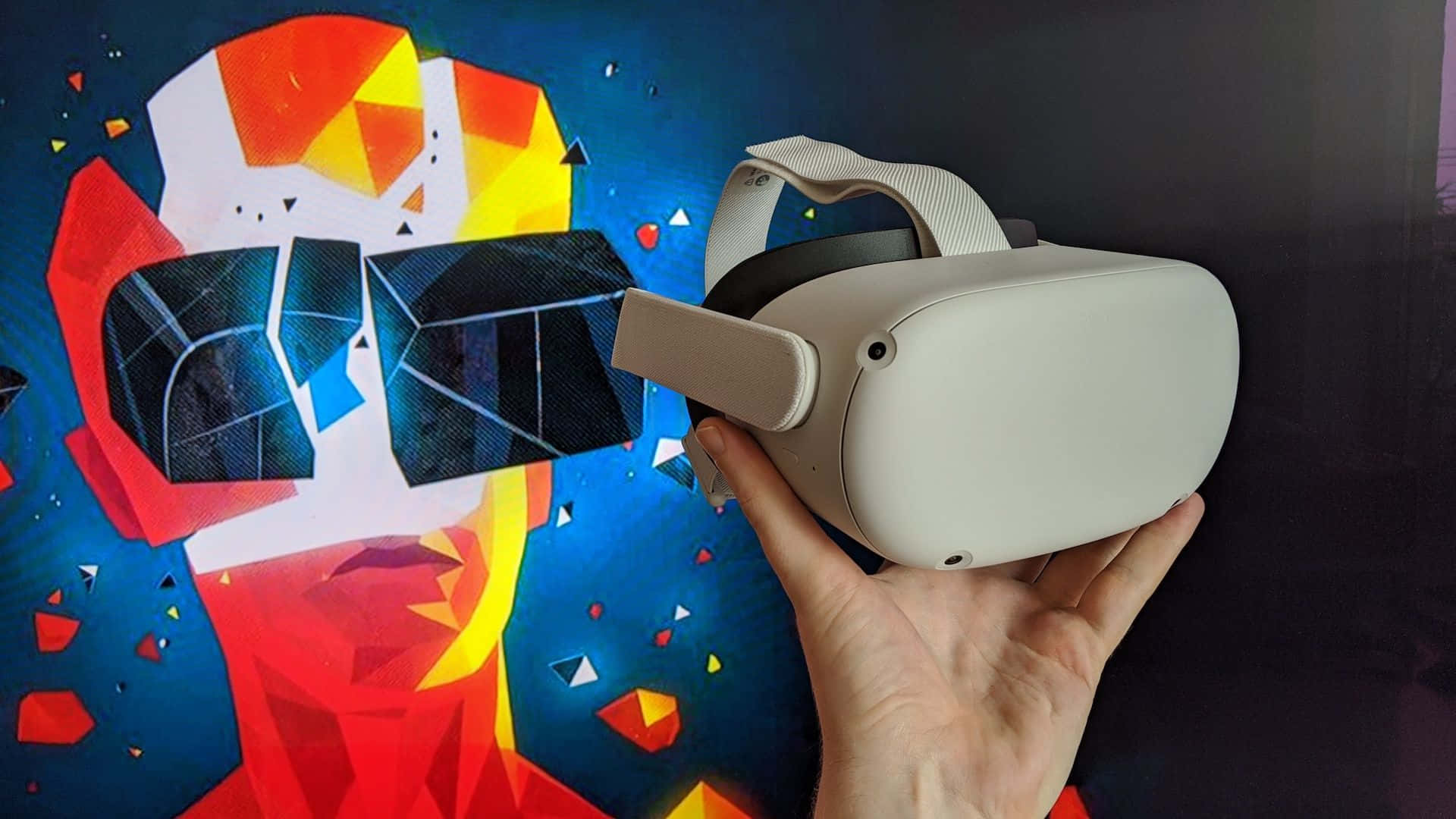 Oculus Quest 2 桌布 壁紙 — 一隻手在一個由紅、黃、藍碎片組成的鮮豔幾何臉部壁畫前，拿著一個白色VR頭戴式裝置。