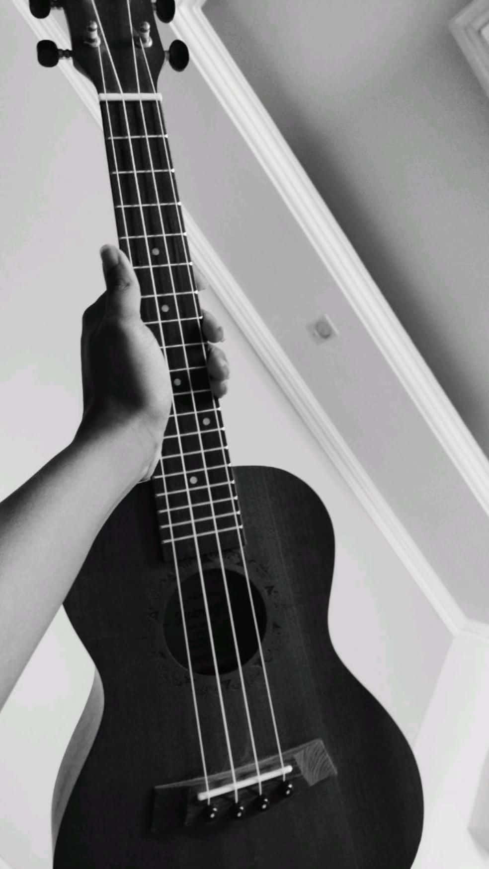 Guitar Aesthetic 桌布 壁紙 — 一隻手在單色室內拍攝中拿著烏克麗麗，帶有柔和陰影和乾淨的建築線條。
