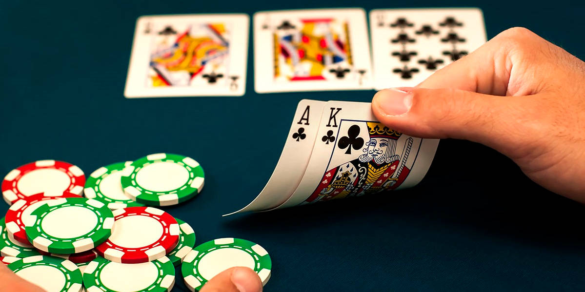 Playing Cards 桌布 壁紙 — 一隻手在撲克桌上揭示梅花A和K，桌上散落著綠色和紅色的籌碼。