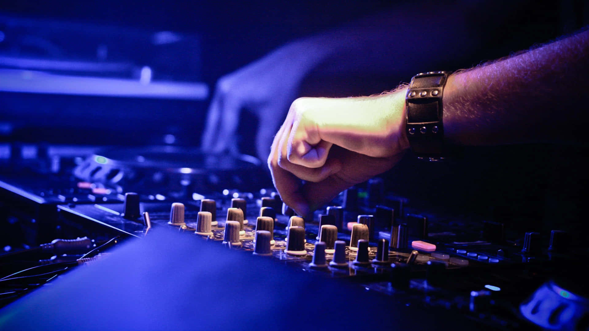 DJ的手在藍色燈光下調整夜總會中的混音器旋鈕。 — DJ GIF 壁紙