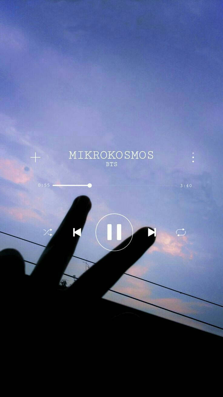Peace Symbol 桌布 壁紙 — 一隻手在暮色天空下做出和平手勢，並帶有顯示BTS的Mikrokosmos的音樂播放器疊加層。