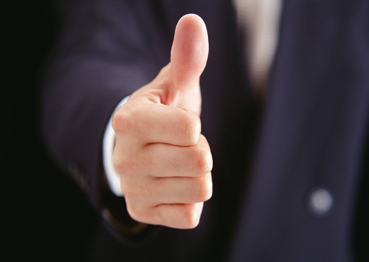 Thumbs Up 桌布 壁紙 — 一隻手在模糊背景下穿著深色西裝比出大拇指的特寫。