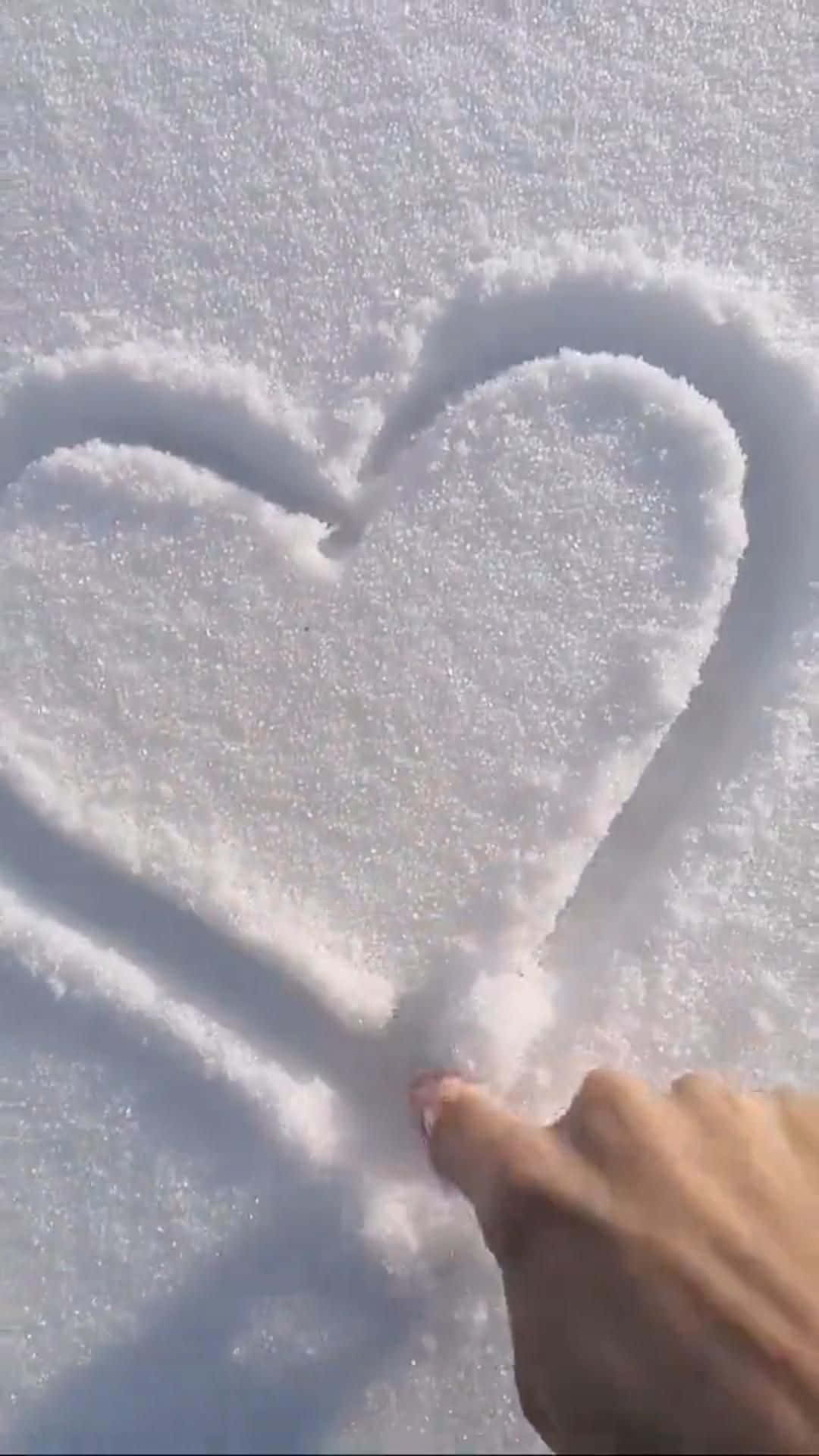 心形美學 桌布 壁紙 — 一隻手在潔白的新雪上畫出心形，明亮的陽光投下柔和的陰影。