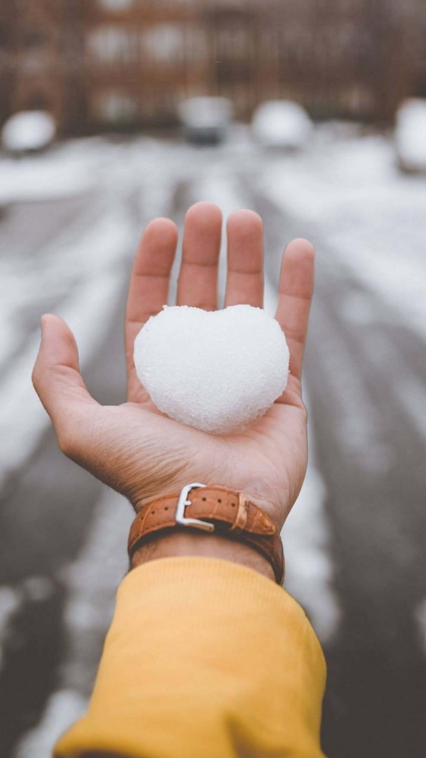 White Heart 桌布 壁紙 — 一隻手在積雪的都市街道背景下拿著一個心形雪球。