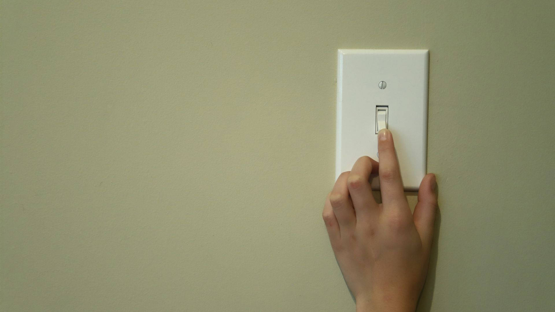 Light 桌布 壁紙 — 一隻手在簡單的室內環境中按下米色牆上的白色燈開關。