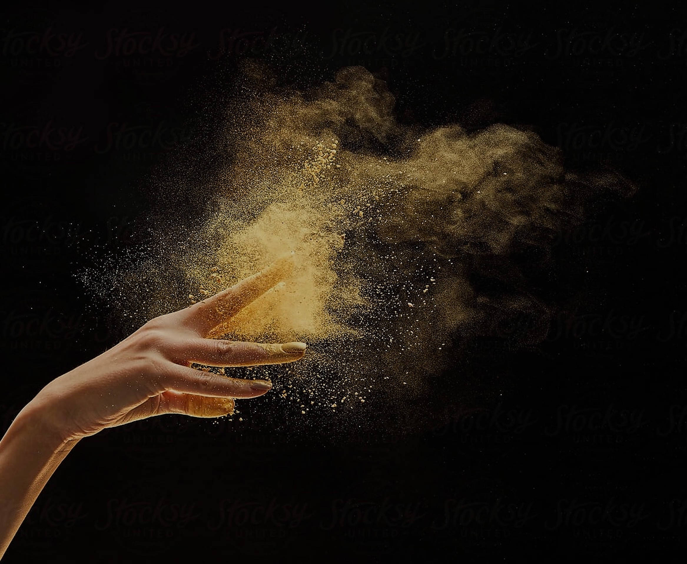 Dust 桌布 壁紙 — 一隻手在純黑背景前釋放出一陣金色塵埃，形成動態的粒子爆炸效果。