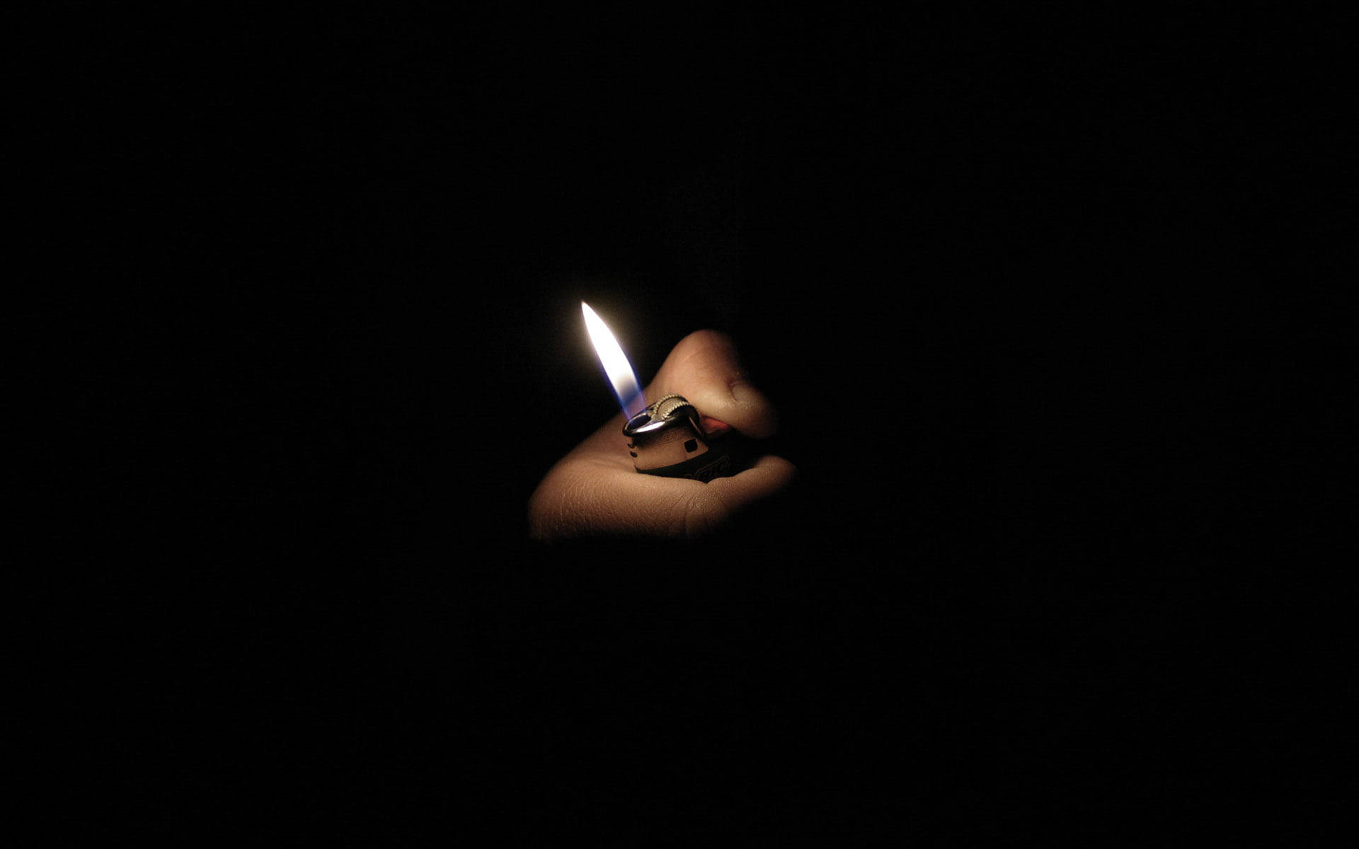 Light 桌布 壁紙 — 一隻手在絕對黑暗中握著一個閃爍的打火機火焰，在皮膚上投射出柔和的光線。