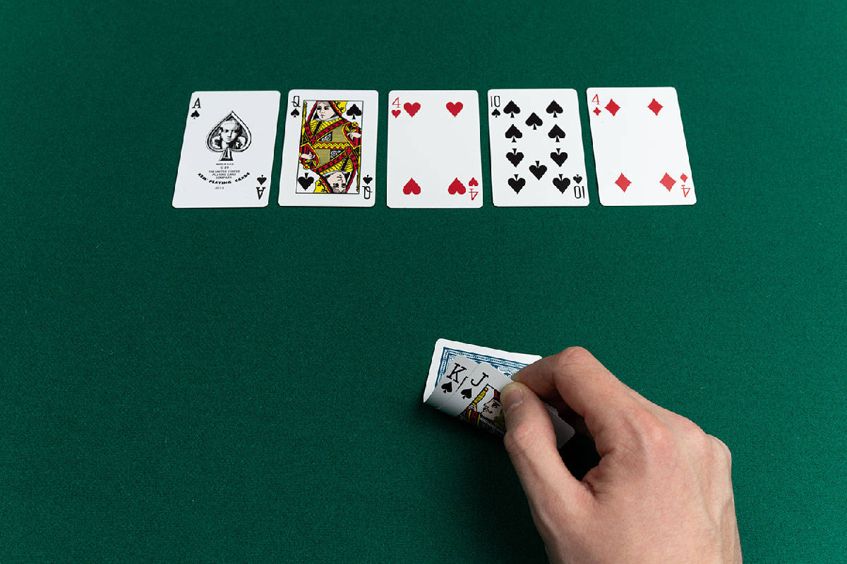 Playing Cards 桌布 壁紙 — 一隻手在綠色氈桌上拿著一張K J撲克牌，桌上排列了五張正面朝上的撲克牌。